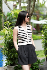 a lady in a striped knit est and a pair of black shorts